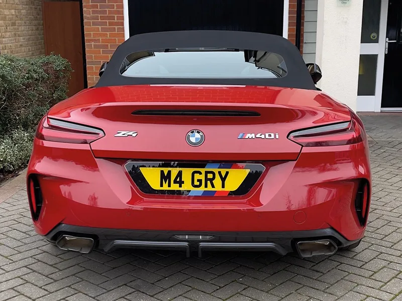 Rear view of a red BMW Z4 M40i convertible, featuring slim LED taillights, twin exhaust outlets and a yellow M Sport-themed shaped number plate displaying “M4 GRY.