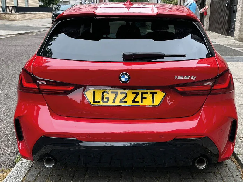 Rear view of a red BMW 128ti, featuring dark rear lights, twin exhaust outlets and a yellow shaped UK registration plate displaying “LG72 ZFT.”