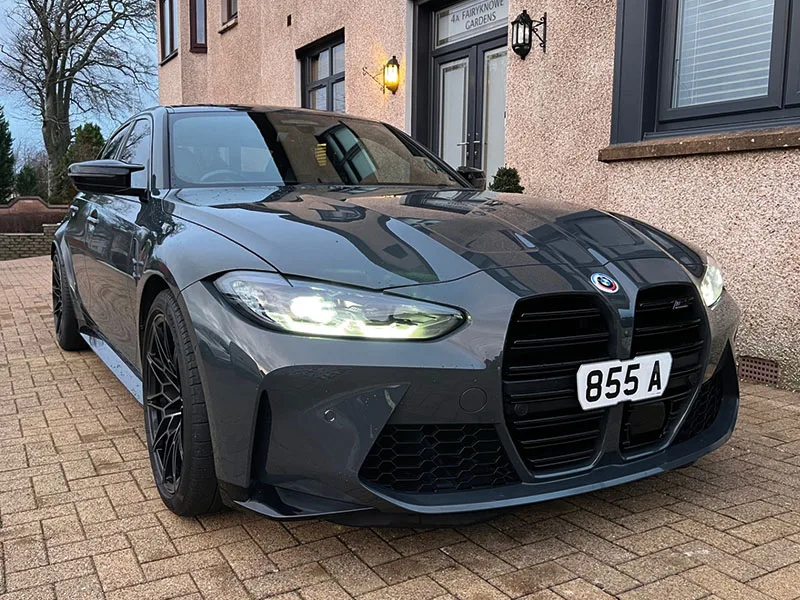 Front three-quarter view of a grey BMW M3 G80 featuring the large black kidney grille, LED headlights and a short white Signature number plate displaying “855 A.”