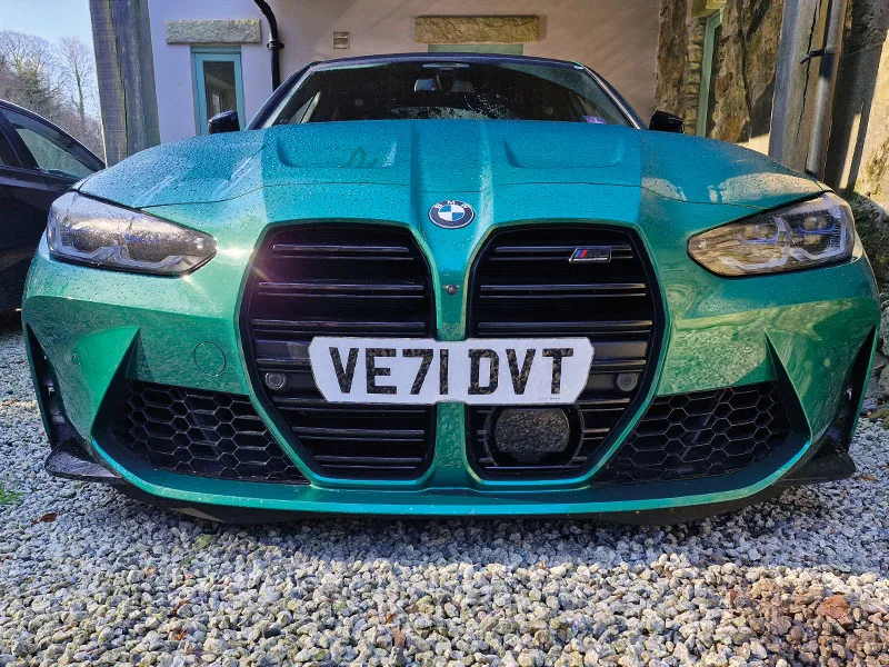 Front view of a green BMW M3 G80 fitted with a white shaped Signature number plate displaying “VE71 DVT” across the kidney grille.