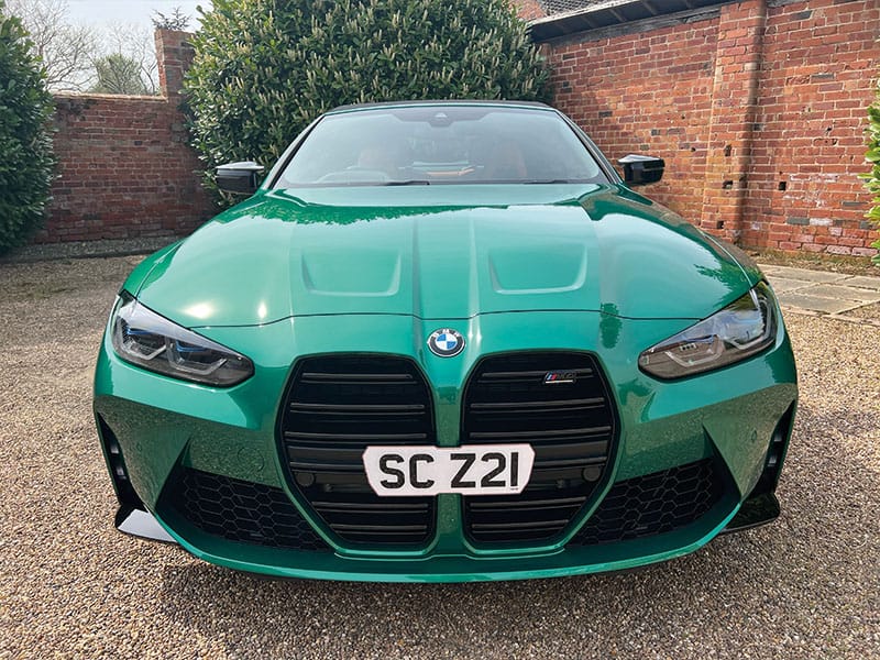 Front view of a green BMW M4 G82 Convertible, featuring the large black kidney grille and a white shaped number plate displaying “SC Z21.”