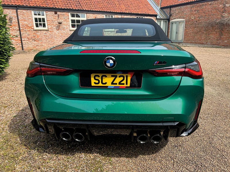 Rear view of a green BMW M4 G82 Convertible, showing quad exhausts, rear diffuser and a yellow M Sport-themed shaped number plate displaying “SC Z21.”