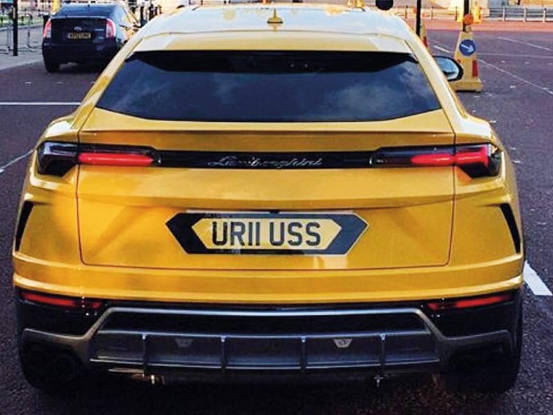 Rear view of a yellow Lamborghini Urus, featuring slim LED taillights, rear diffuser and a shaped number plate displaying “UR11 USS.”