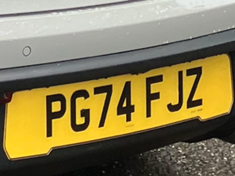Close-up of a Porsche Macan rear bumper fitted with a yellow fully reflective shaped number plate displaying “PG74 FJZ.”
