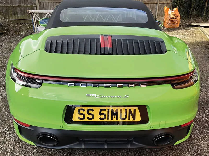 Rear view of a bright green Porsche 911 Carrera S Cabriolet, featuring the full-width rear light bar, twin exhaust outlets and a yellow black-surround number plate displaying “S5 5MMN.”