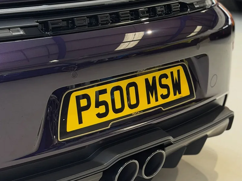 Close-up rear view of a purple Porsche 911 GT3, featuring black Porsche badging, twin central exhaust outlets and a yellow black-surround shaped number plate displaying “P500 MSW.”